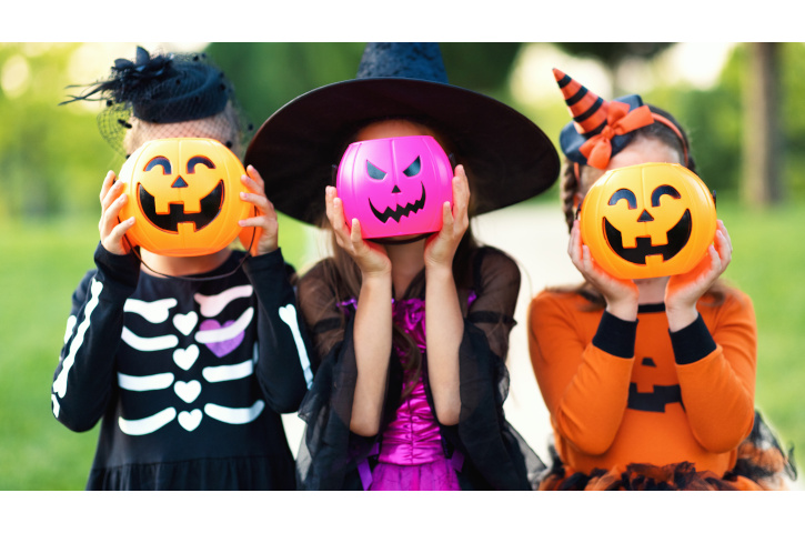 Happy Halloween! funny kids girls in fancy dress hide their heads behind buckets pumpkins outdoors