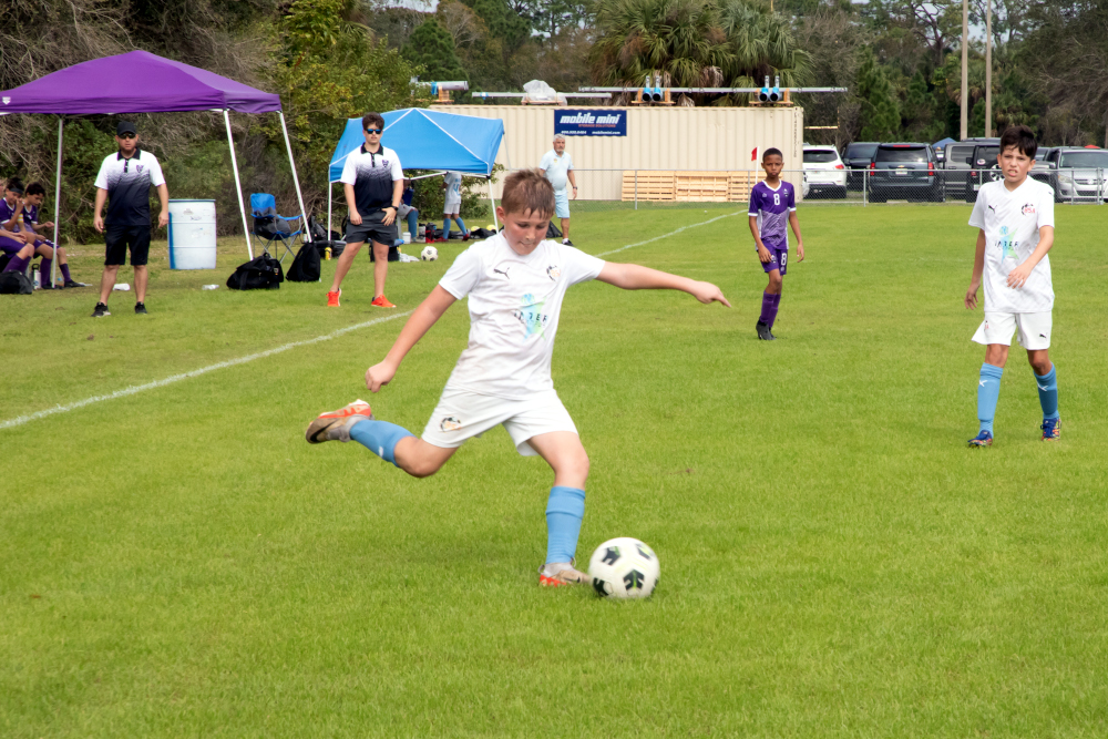 Kid kicks a soccer ball at mitchell ellington